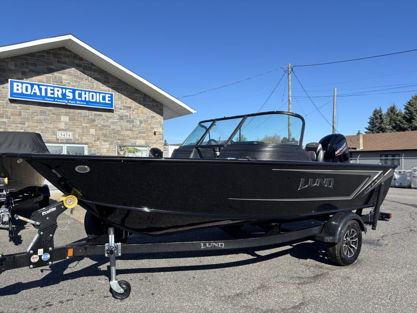 A sleek black fishing boat parked on a trailer outside a stone building.