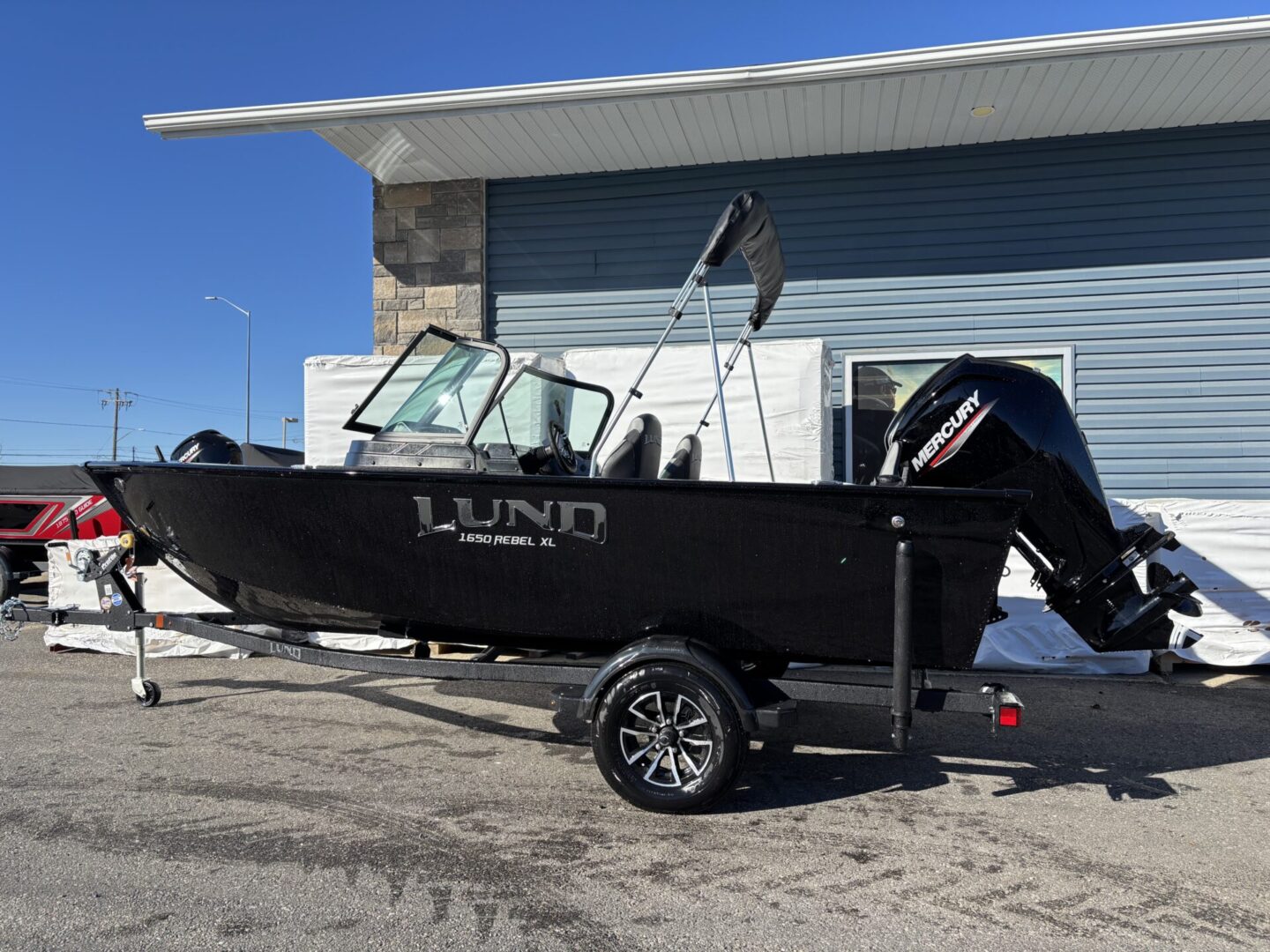 Black Lund fishing boat on trailer parked outside a building.
