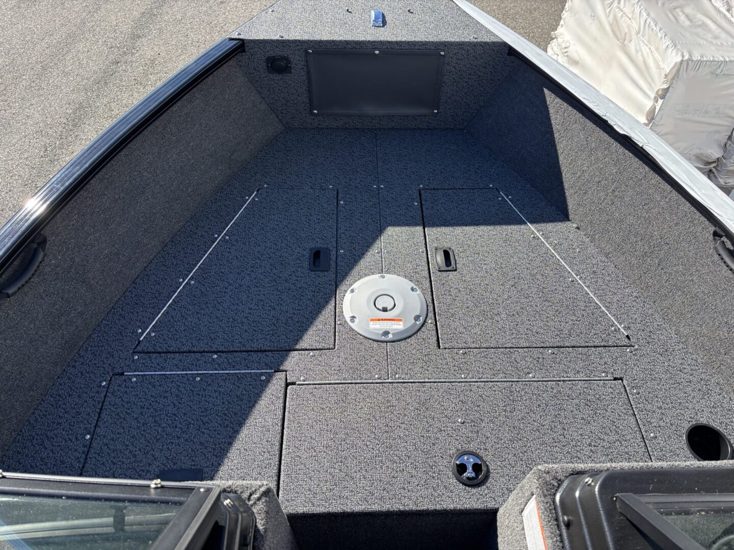 Carpeted boat deck with storage compartments and a fishing seat base.