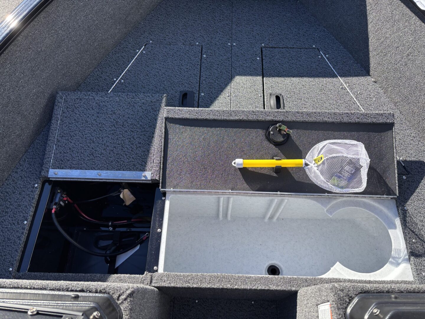 Fishing rod and net on a boat deck with storage compartments.