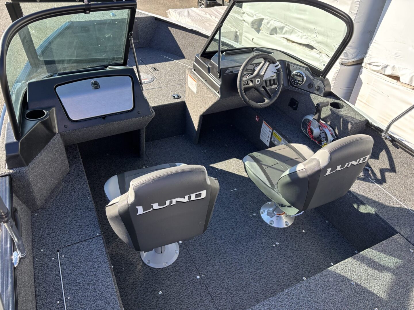 Interior of a modern fishing boat with two seats and a steering wheel.