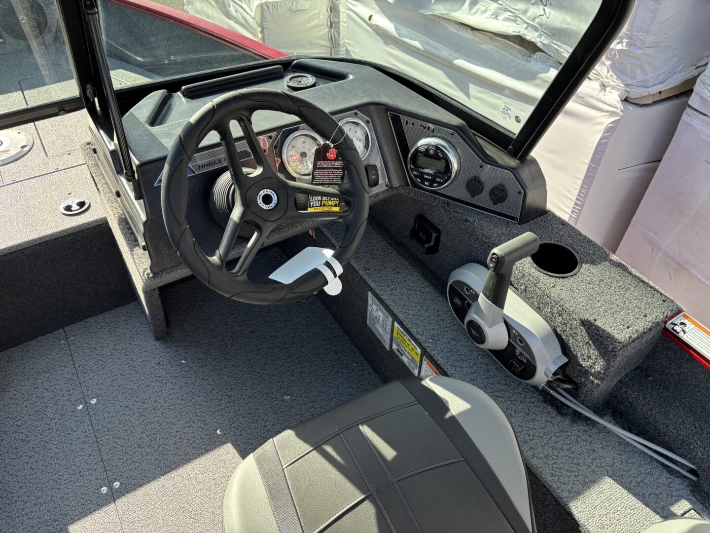 Interior of a modern boat cockpit with steering wheel and controls.