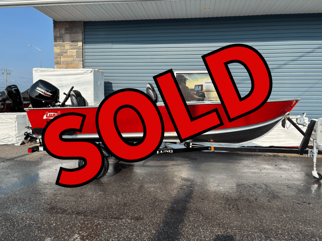 White boat parked at a marina with a large red SOLD sign.