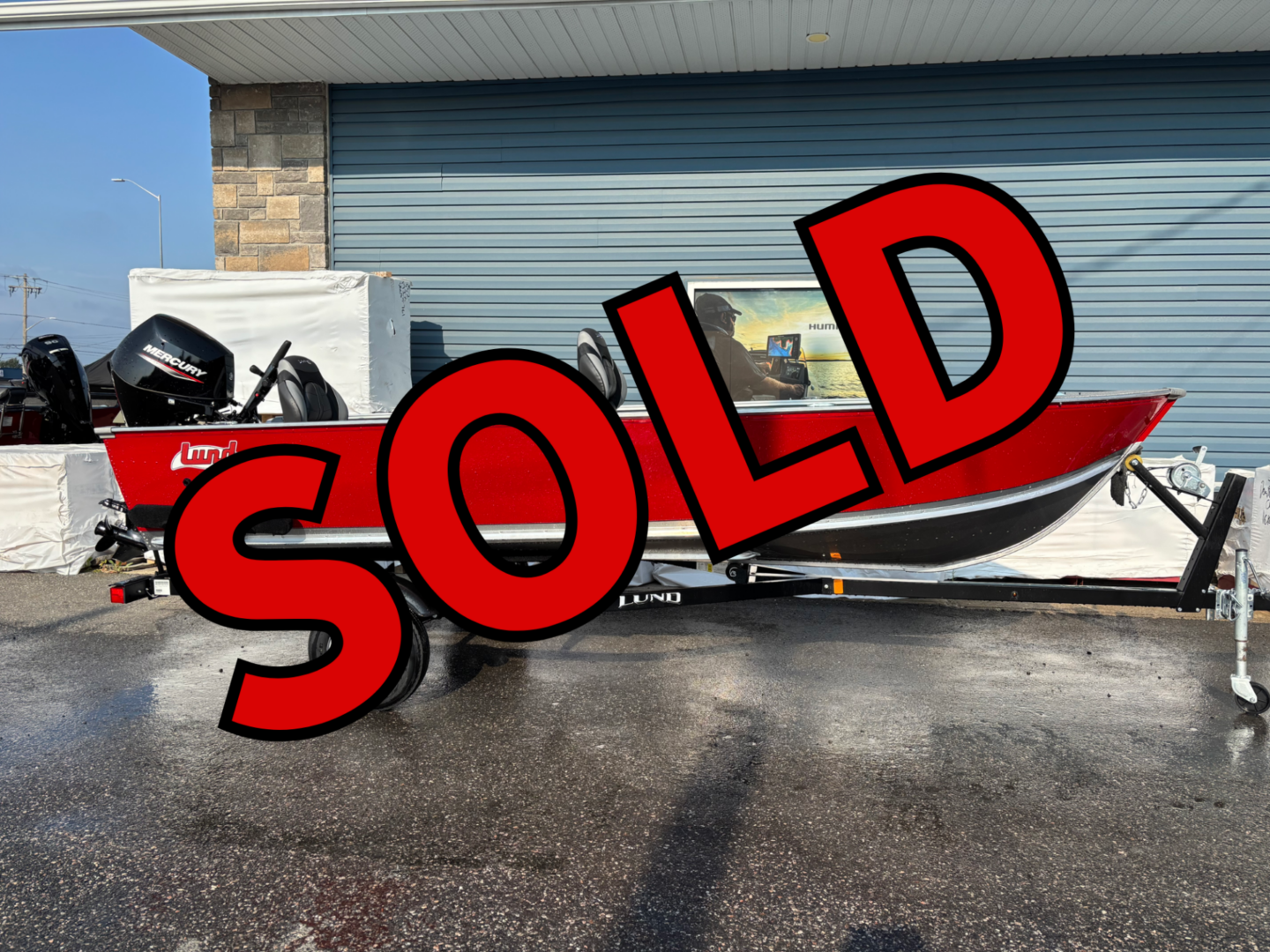 White boat parked at a marina with a large red SOLD sign.