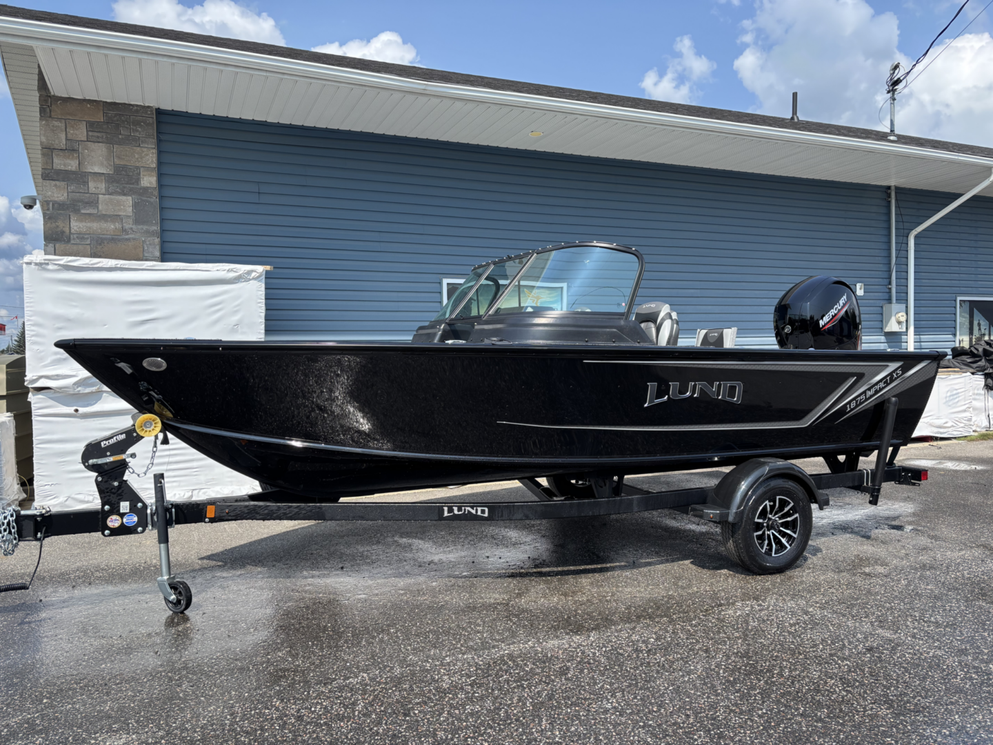 A sleek black Lund fishing boat on a trailer under a blue sky.
