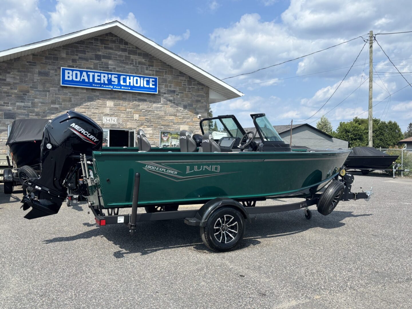 Green fishing boat on a trailer outside a boater's choice shop.
