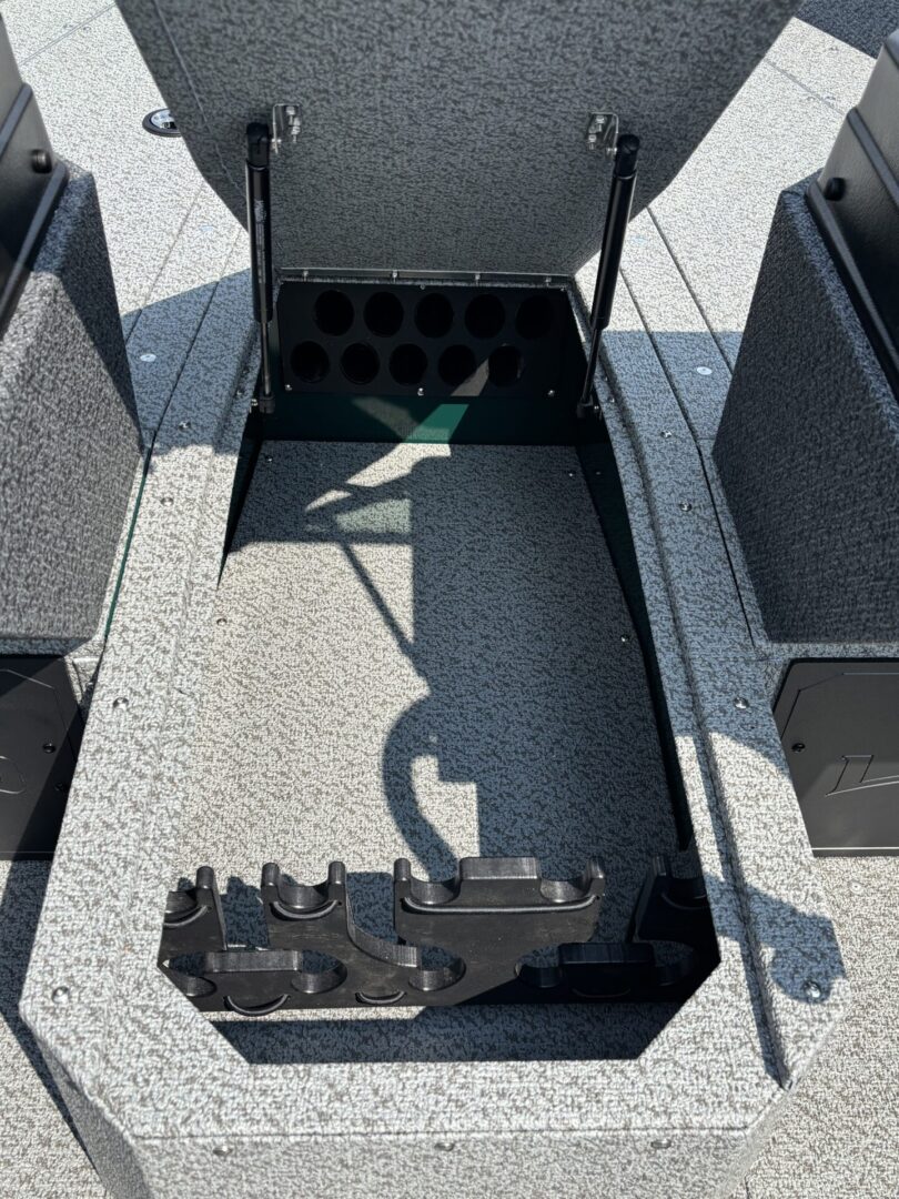 Empty gray boat interior with fishing rod holders and storage compartments.