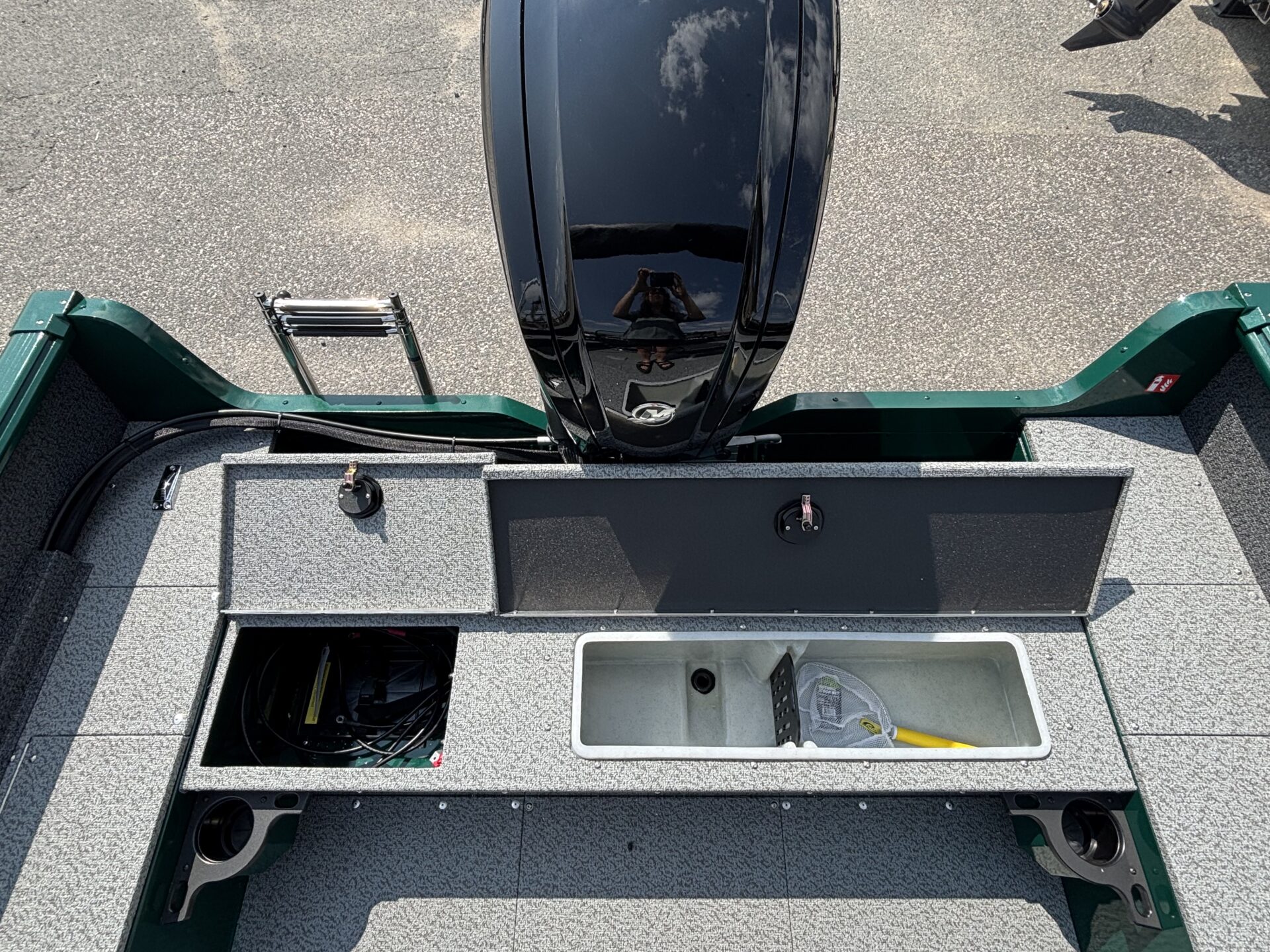 Boat deck with storage compartments and an outboard motor.