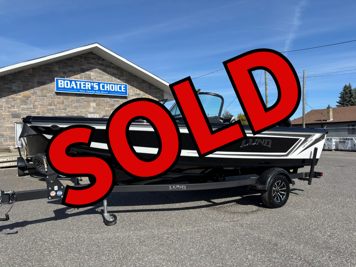 Boat for sale with a large SOLD sign in front of a boathouse.