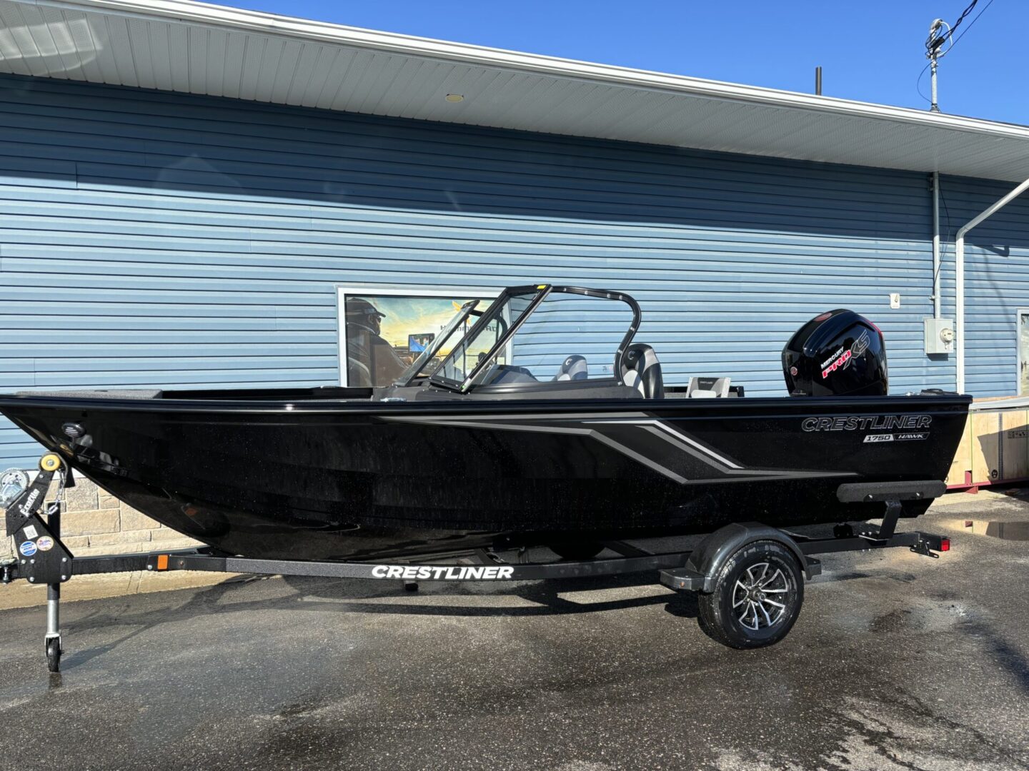A sleek black fishing boat on a trailer in front of a building.