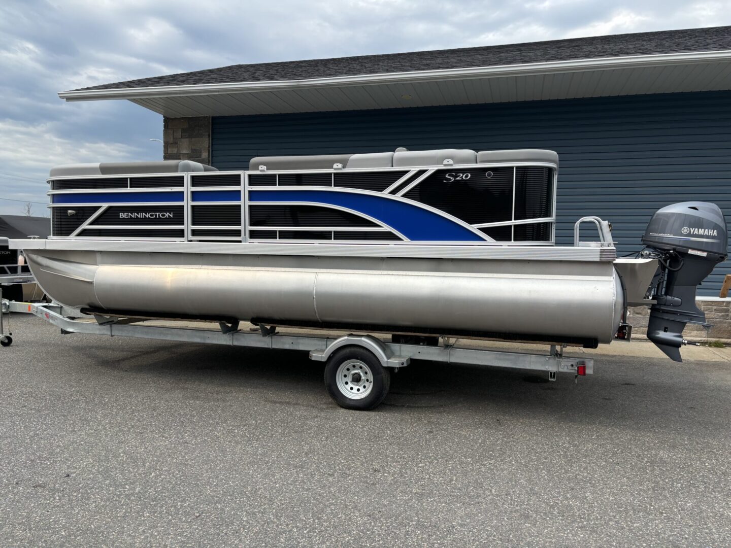 A pontoon boat on a trailer outside a building.