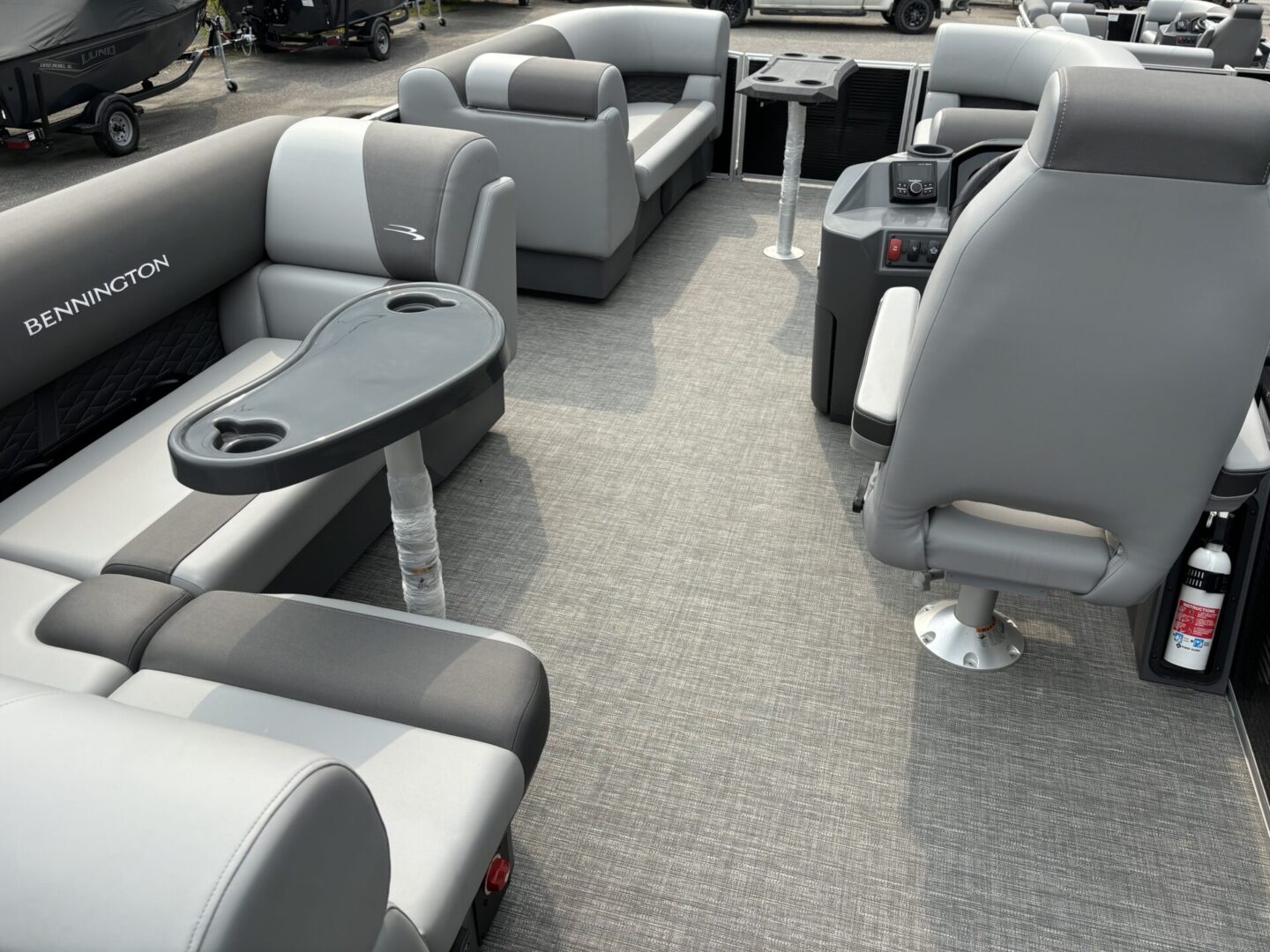 Interior view of a modern pontoon boat with gray cushioned seats and a carpeted floor.