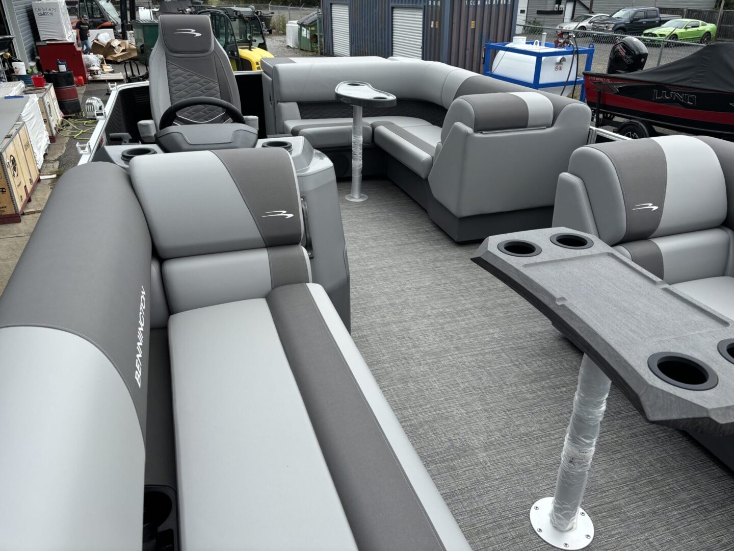 Spacious gray and white pontoon boat seating with cup holders.
