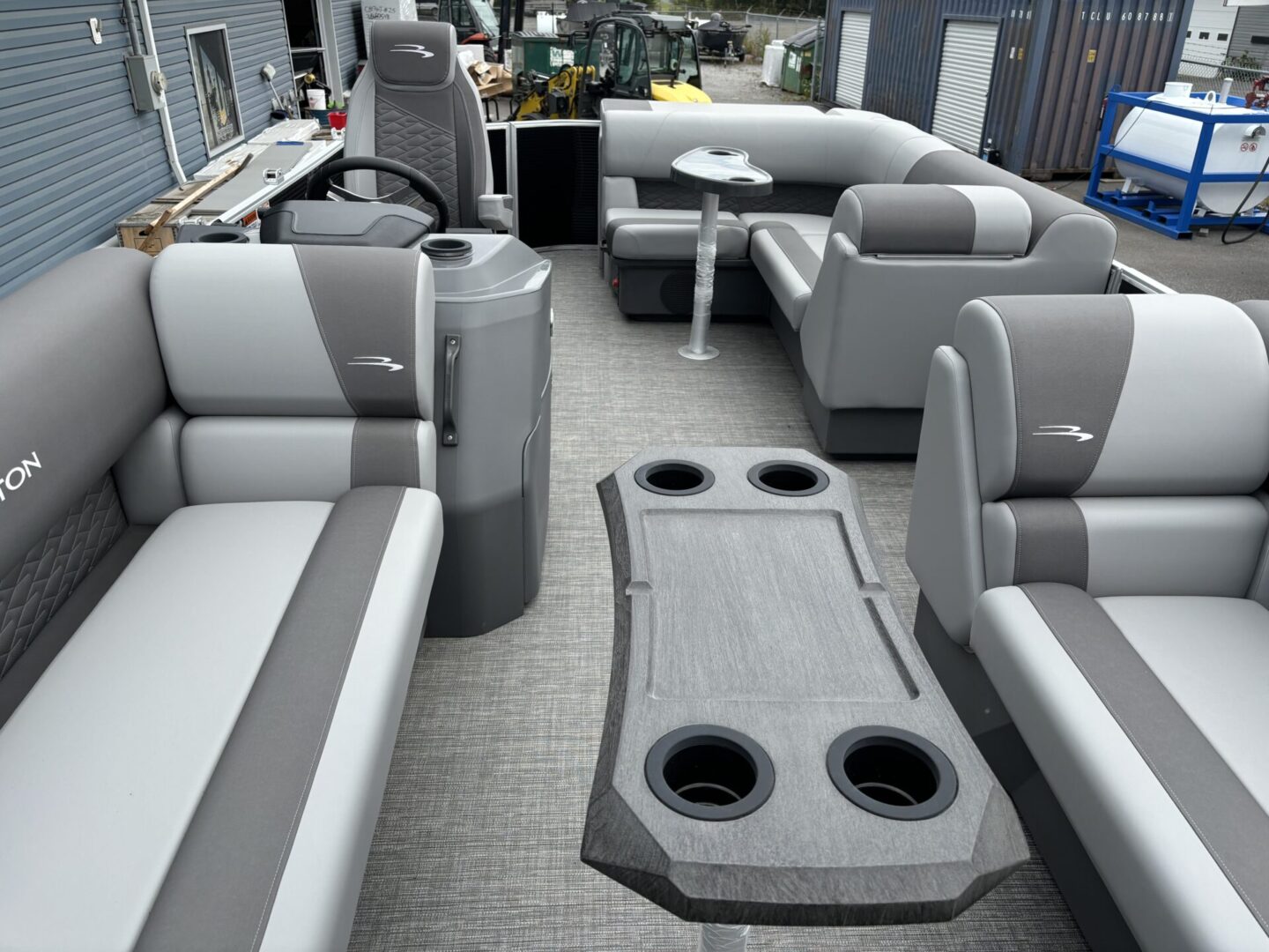 Spacious pontoon boat seating with cup holders and gray upholstery.
