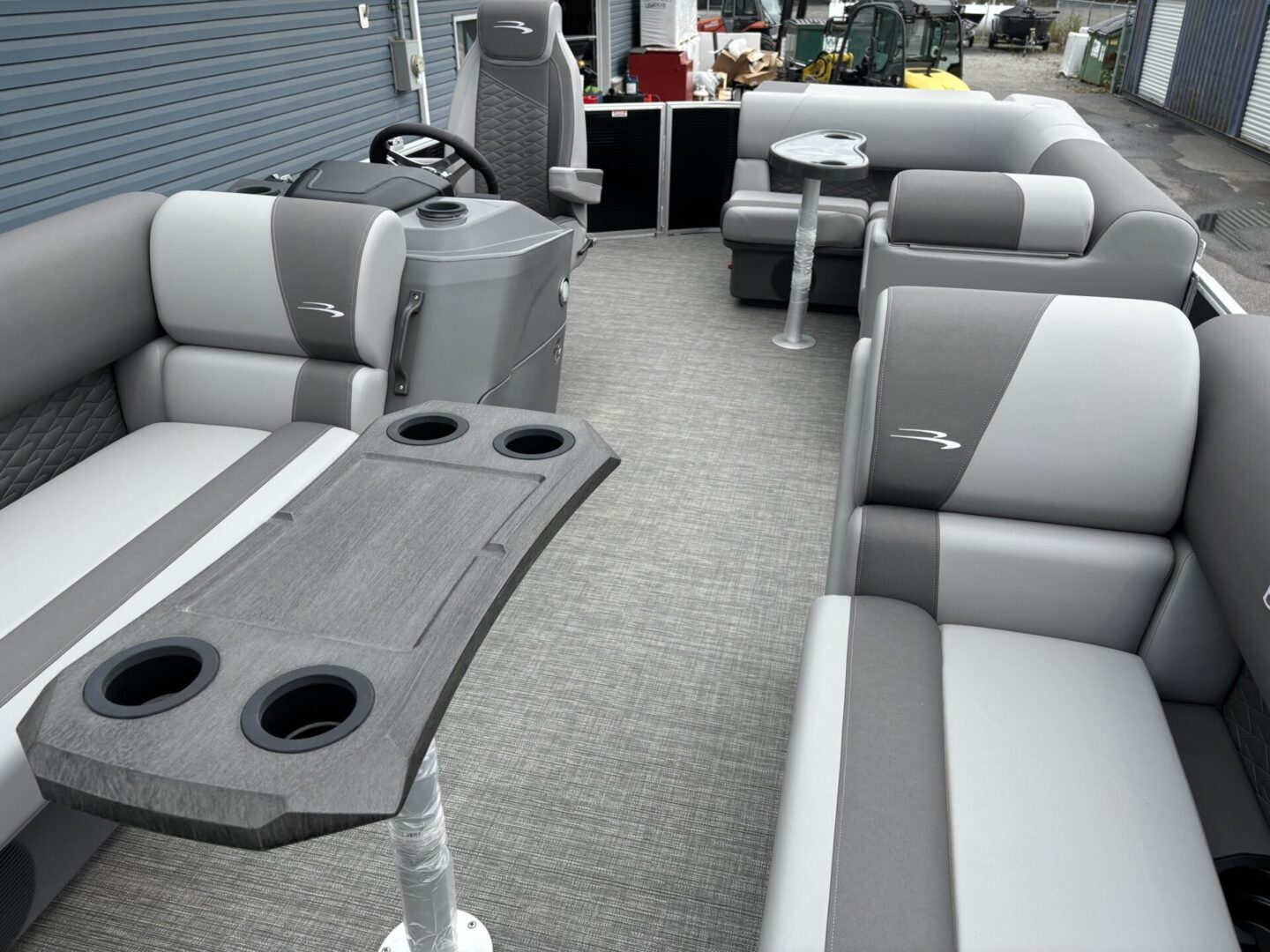 Interior of a modern pontoon boat with cushioned seating and cup holders.