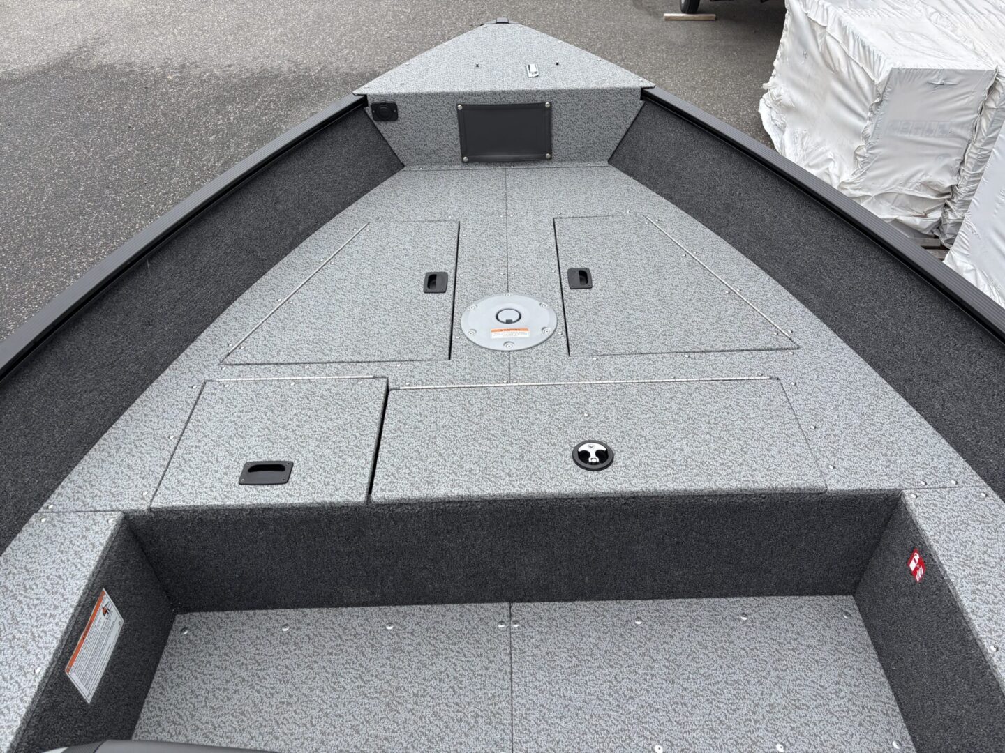 Gray carpeted boat deck with storage compartments and seating area.