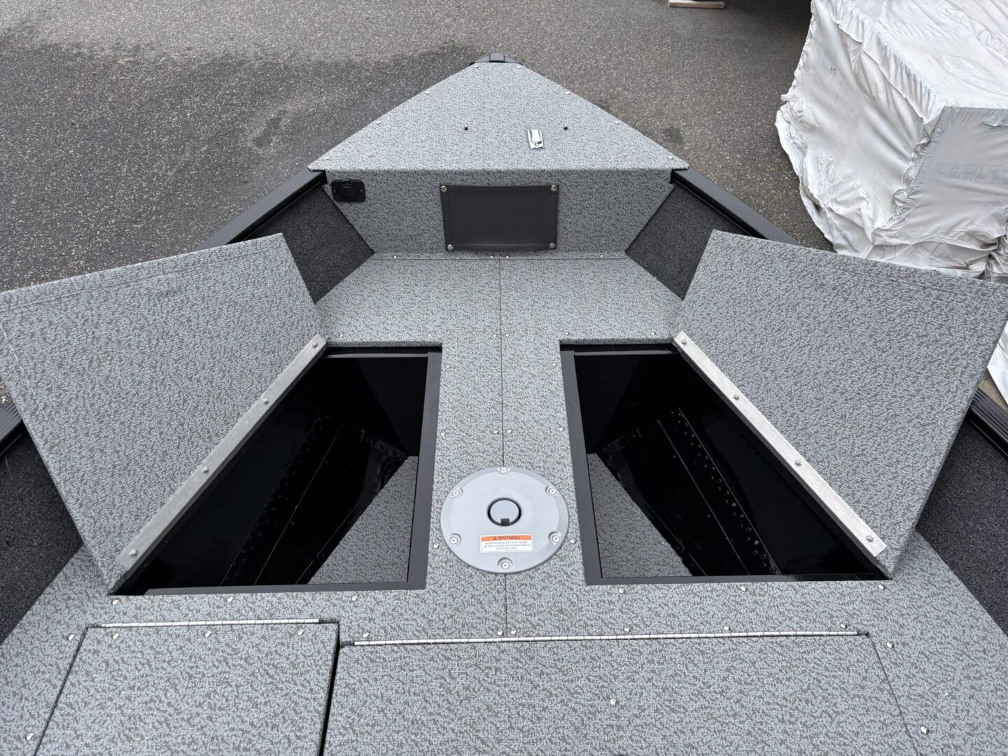 Bow area of a fishing boat with storage compartments open.