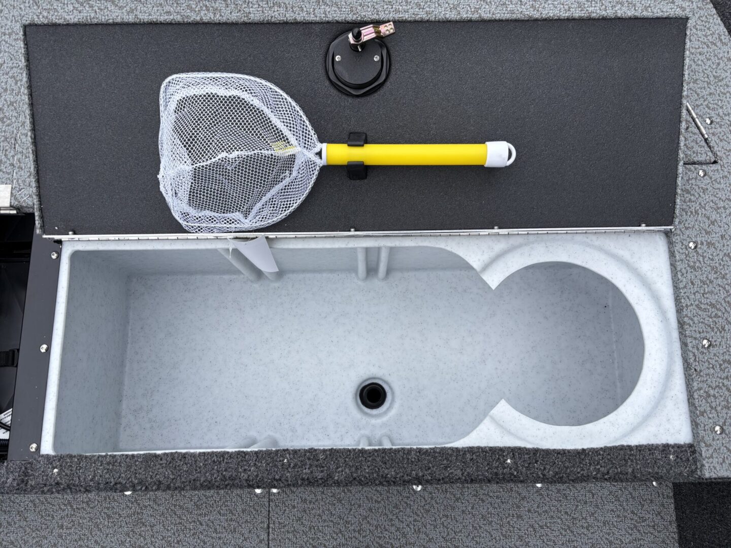 Boat fishing setup with a net and livewell compartment.