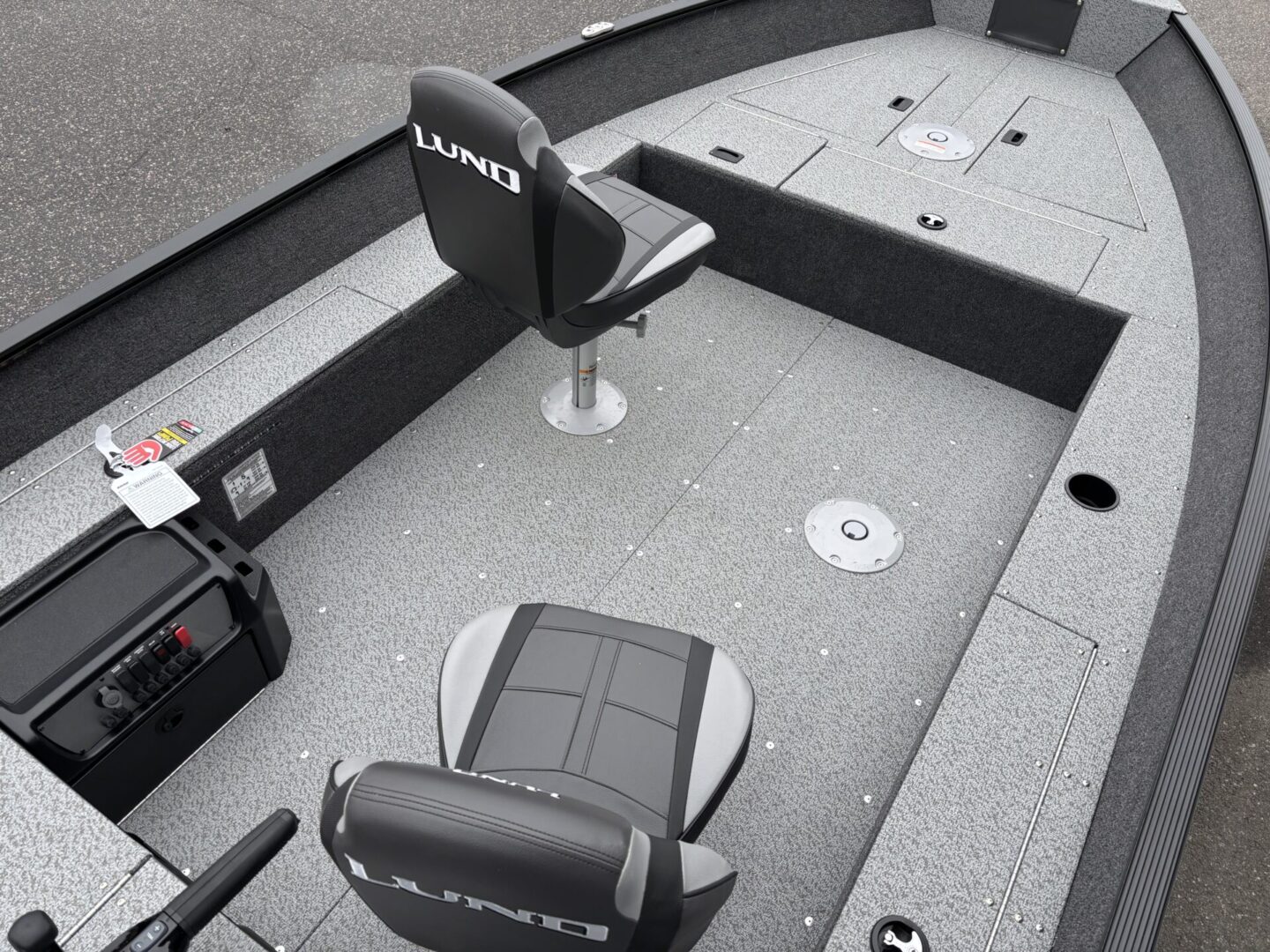 Interior of a fishing boat with two swivel chairs and a textured floor.