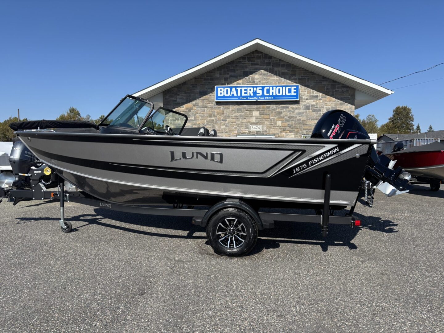 Sleek black and silver fishing boat on a trailer outside a boat sales shop.