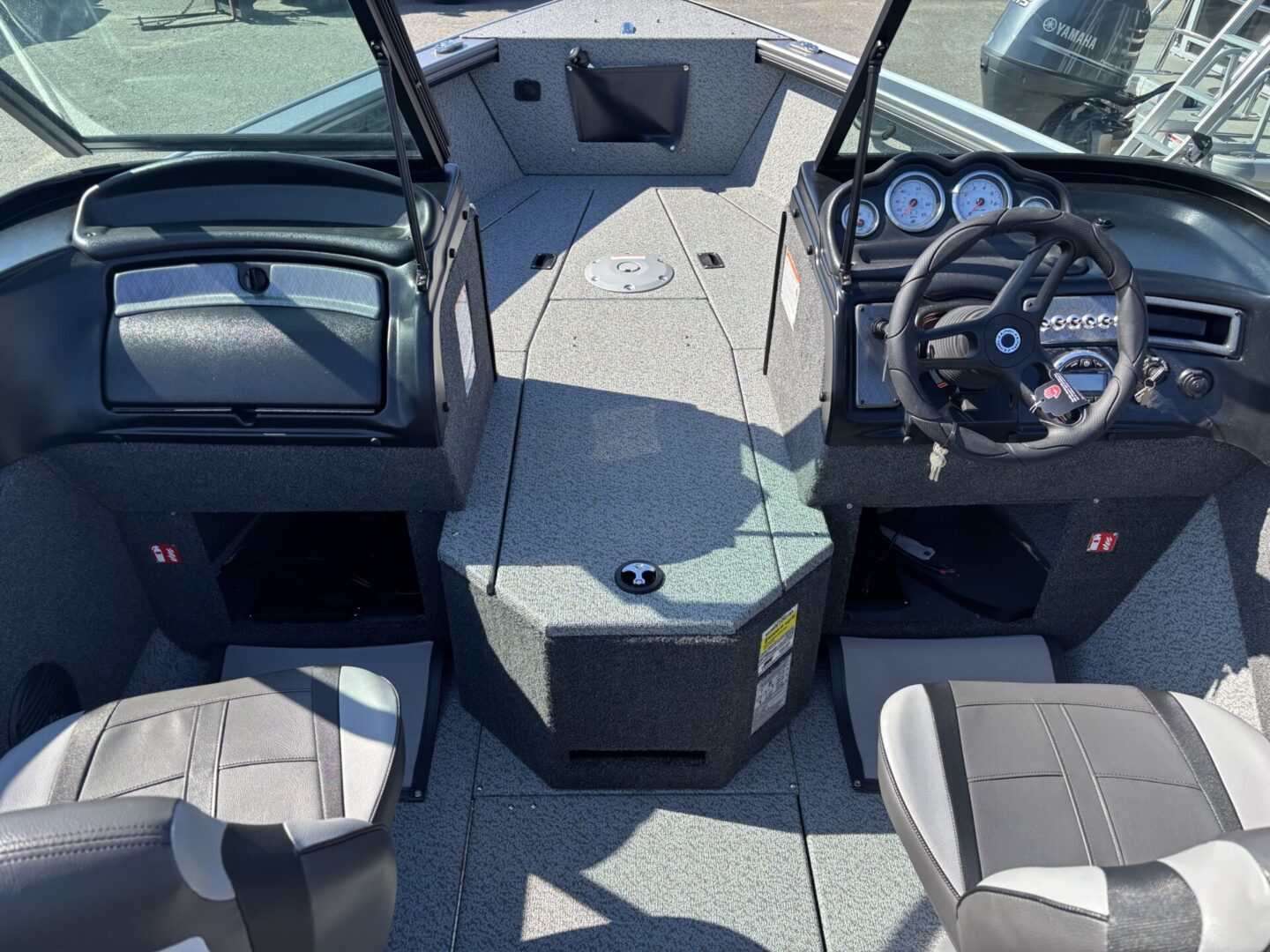 Boat deck with steering wheel and seating under a clear sky.