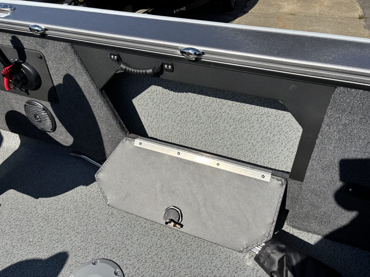 Open compartment inside a vehicle trunk with carpeted interior.
