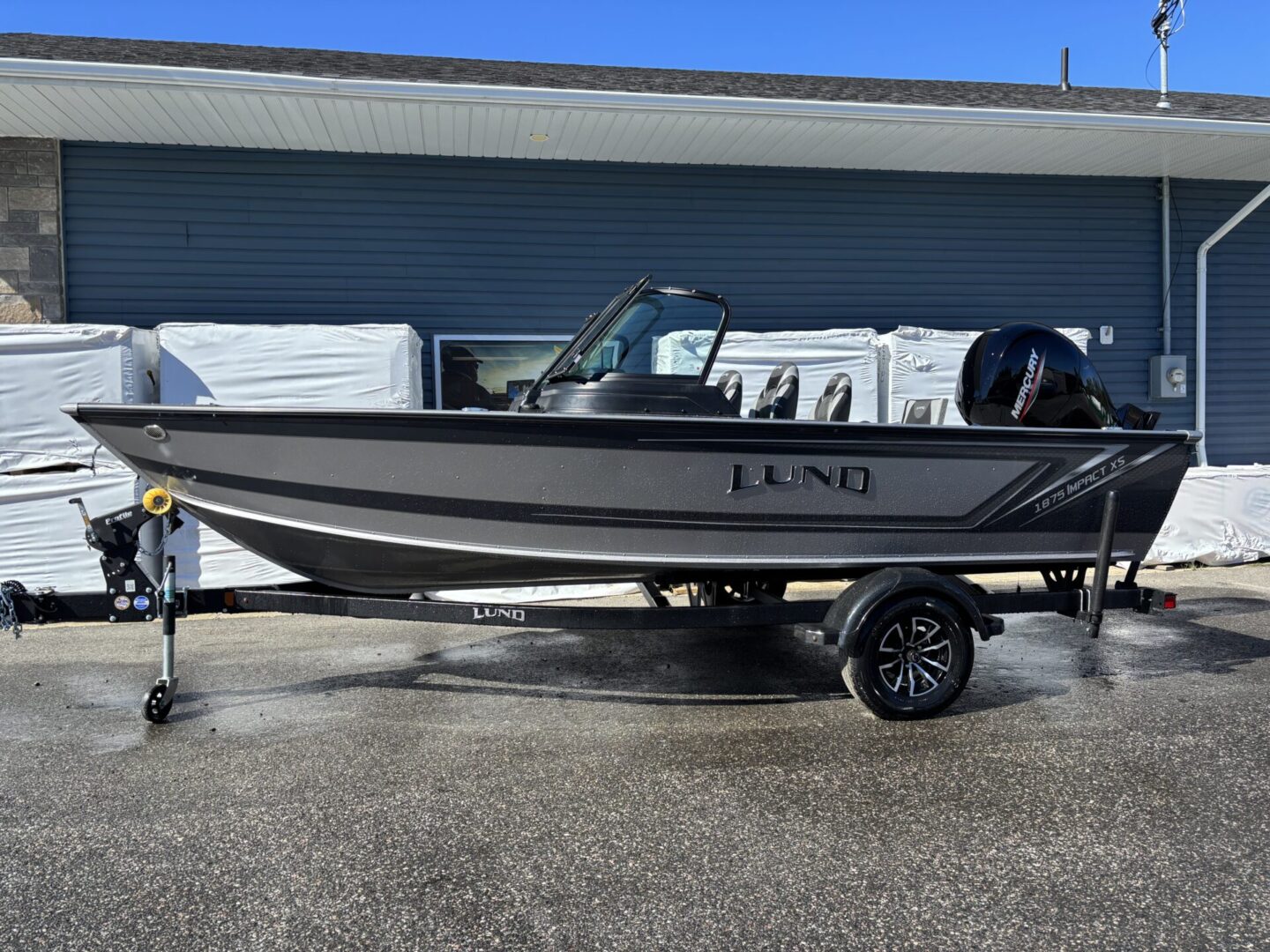 A black and gray fishing boat parked on a trailer in front of a building.