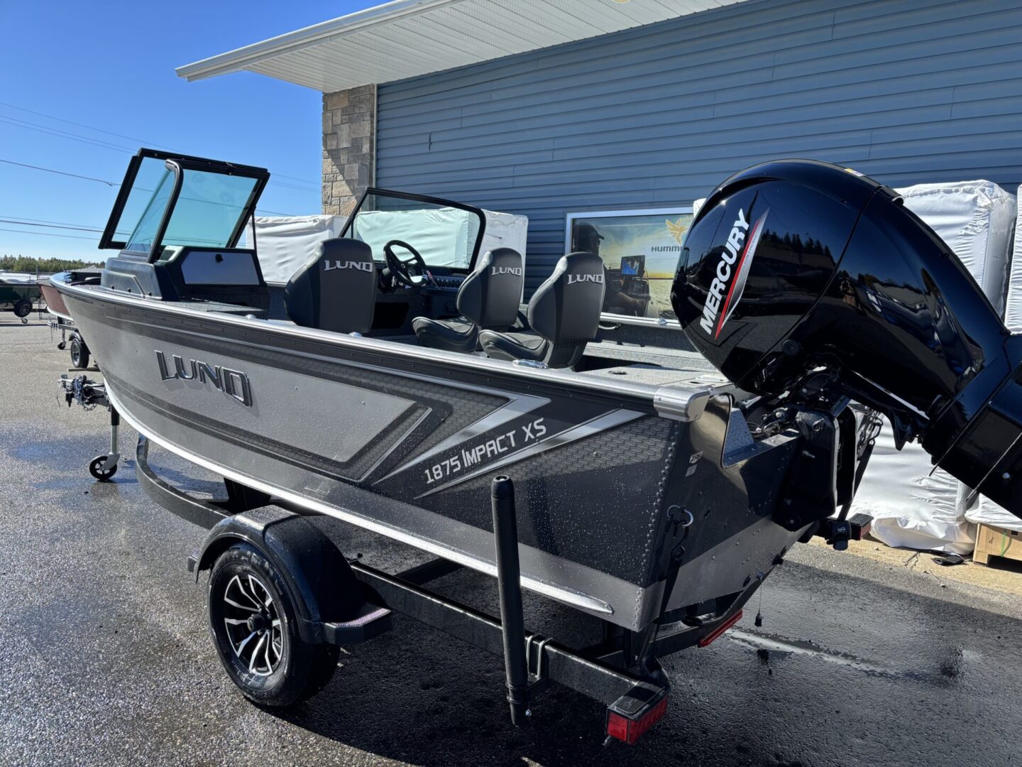 A sleek aluminum fishing boat with an outboard motor parked on a trailer.
