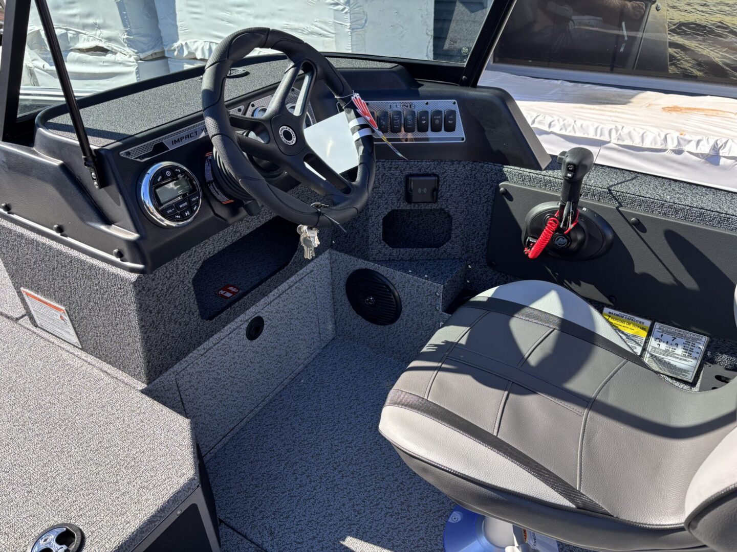 Modern boat cockpit with steering wheel and control panel.