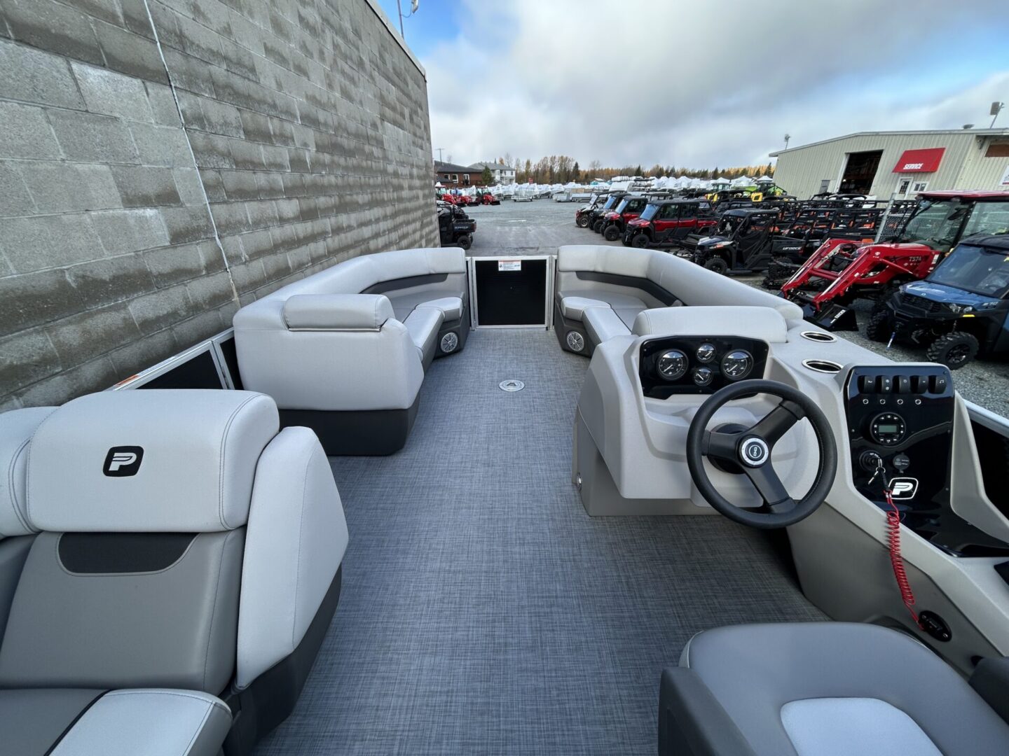 Spacious pontoon deck with gray seating and helm
