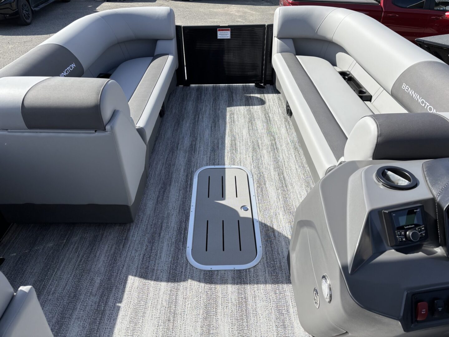 Interior view of a modern pontoon boat with stylish seating and wood-patterned flooring.