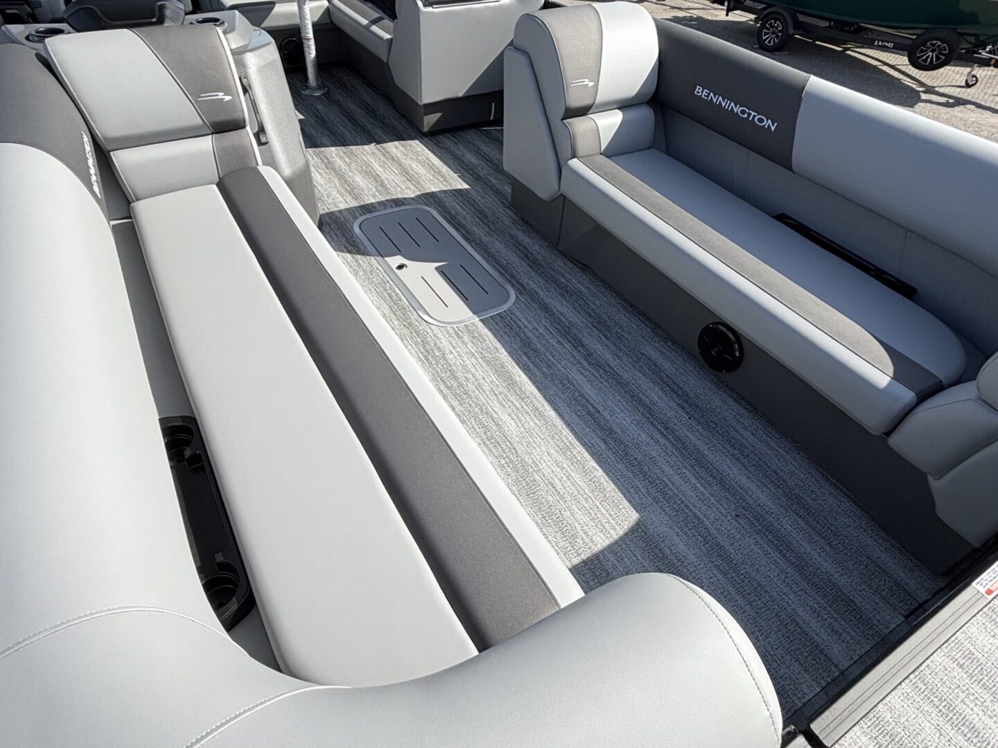 Modern boat interior with cushioned seating and wood-style flooring.