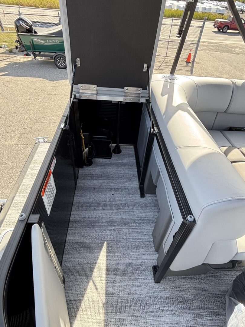Open storage compartment on a boat with cushioned seating nearby.