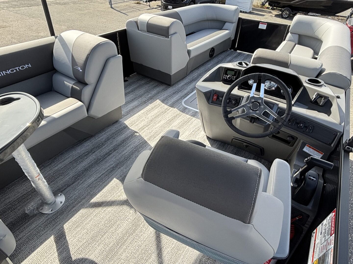 Modern boat interior with gray cushioned seats and steering console.