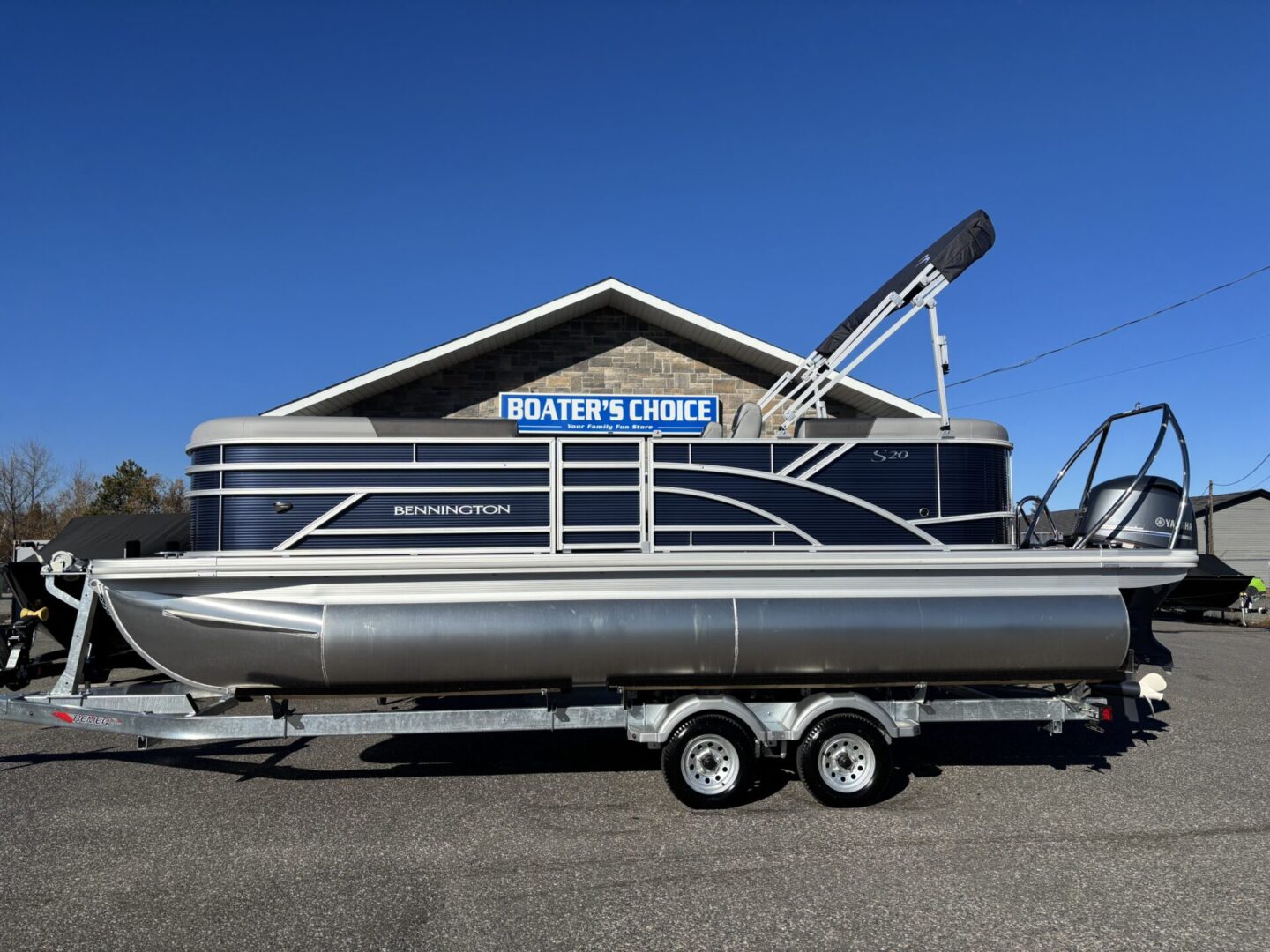 A pontoon boat parked in front of a building under clear blue sky.