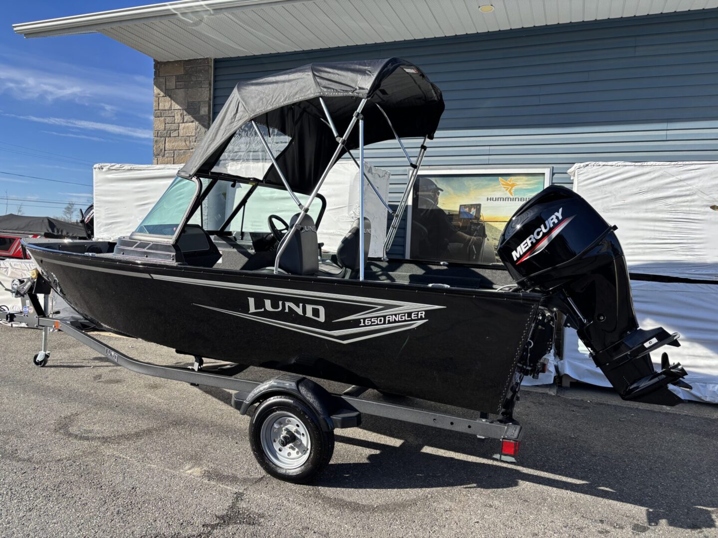 Black Lund fishing boat on a trailer with a motor.