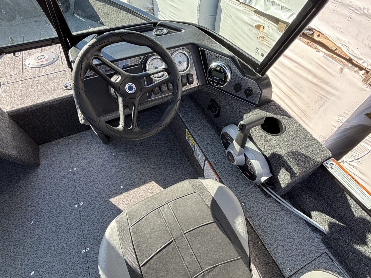 Interior view of a vehicle driver's seat and dashboard with steering wheel.