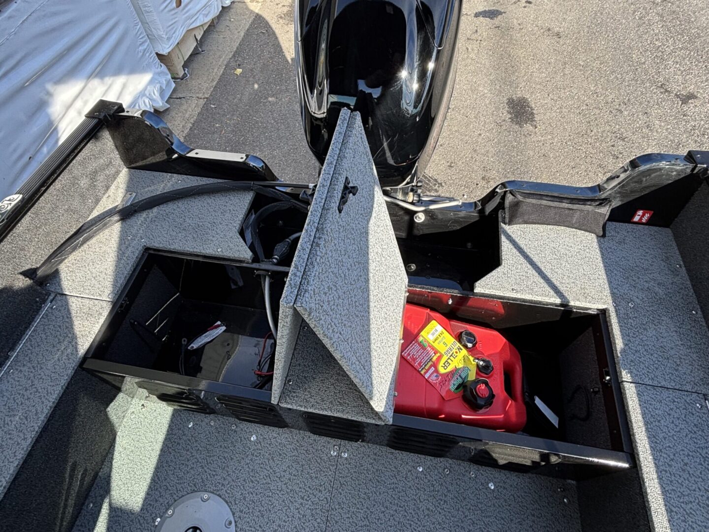 Open storage compartment on a motorcycle showing a red fuel container inside.