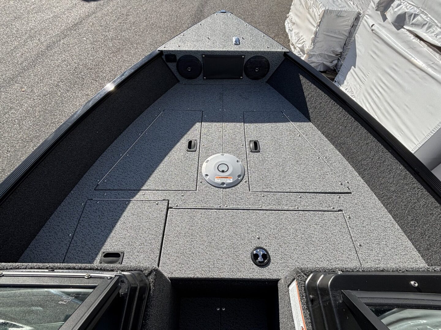 Front deck of a fishing boat with storage compartments and rod holders.