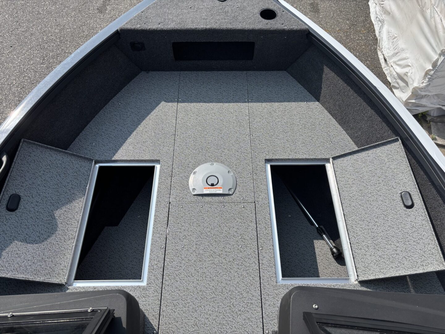 Front deck of a fishing boat with storage compartments and carpeted flooring.