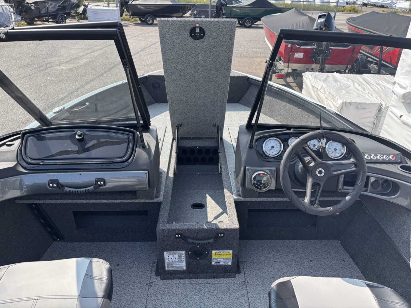 View of a boat's helm with steering wheel and control panel.