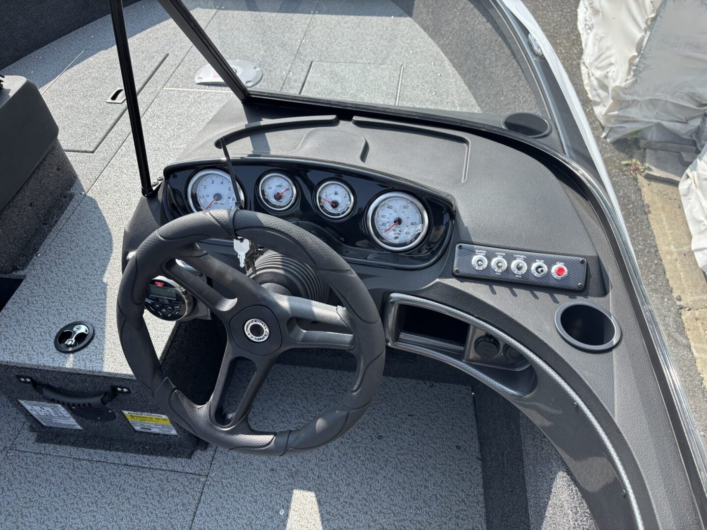Boat steering wheel and dashboard with gauges and controls.