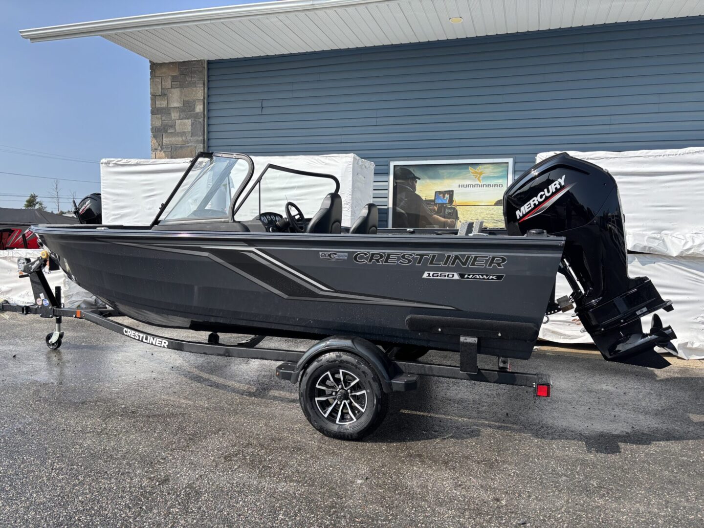 Black motorboat on a trailer parked outside a building.