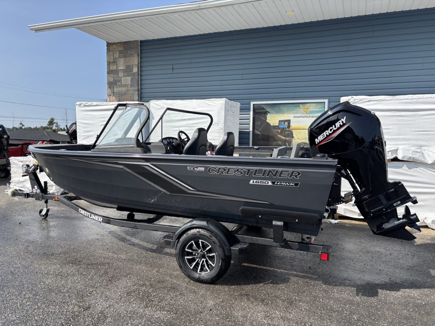 A sleek black motorboat on a trailer, parked outside a building.
