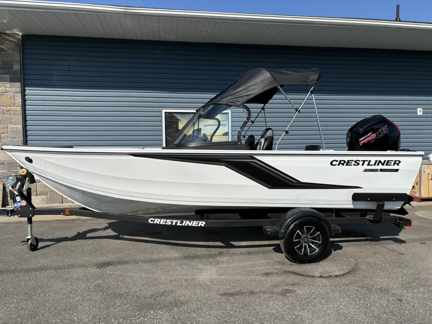 A sleek Crestliner motorboat parked on a trailer outside a building.
