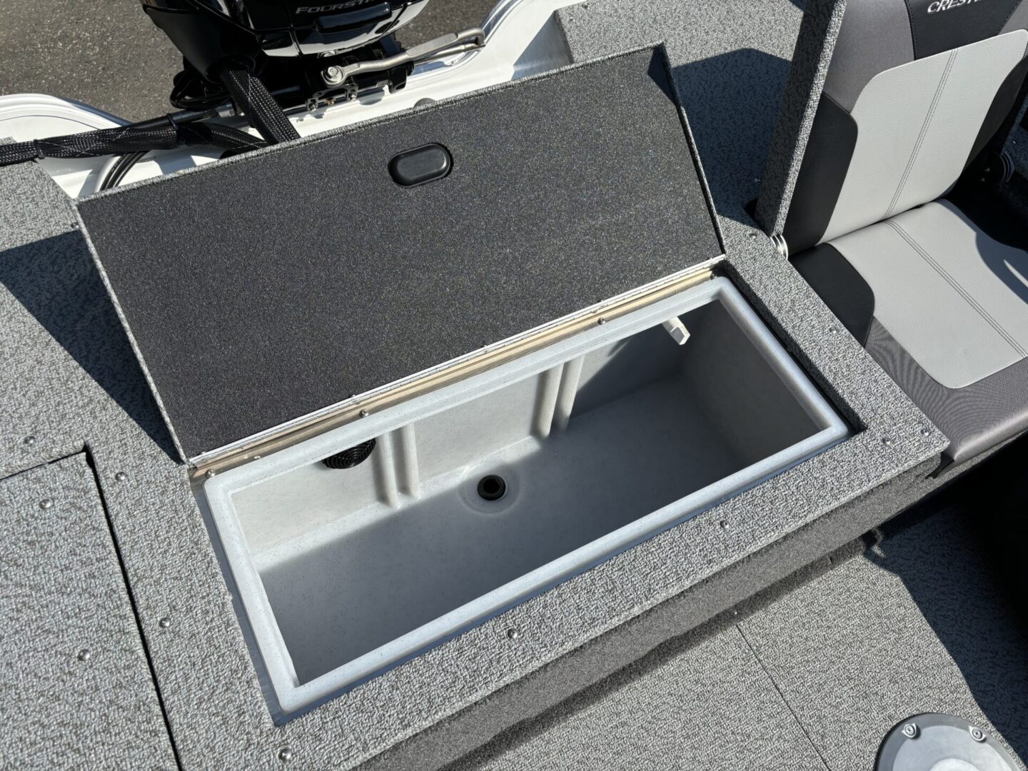Open storage compartment on a boat deck with gray carpeting.