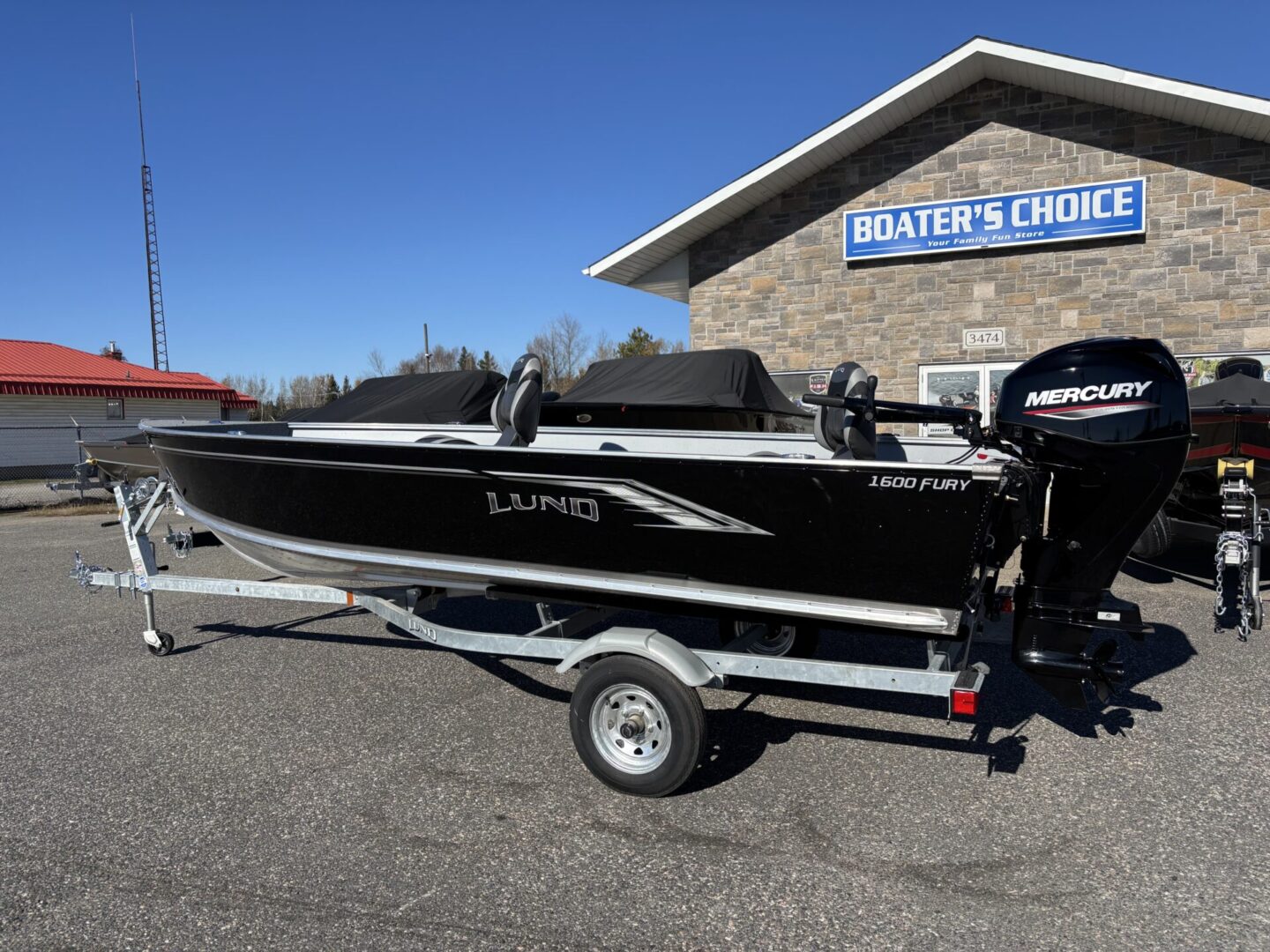 Black and silver boat on a trailer under a clear blue sky.