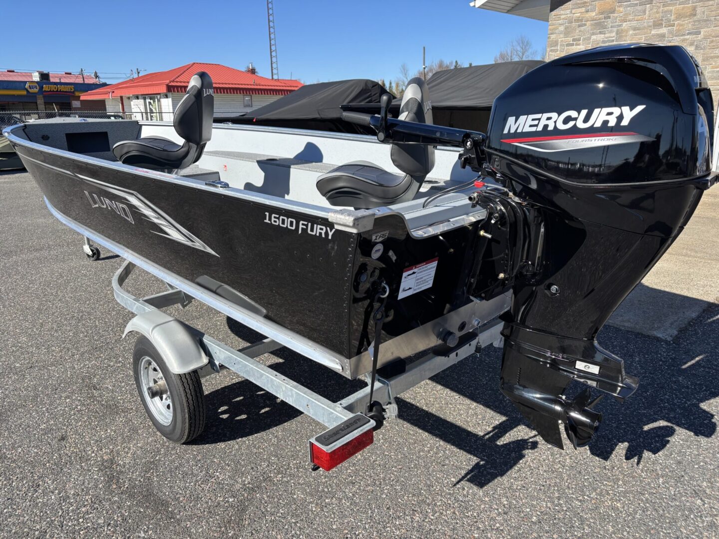 Black and white fishing boat on a trailer with a Mercury outboard motor.