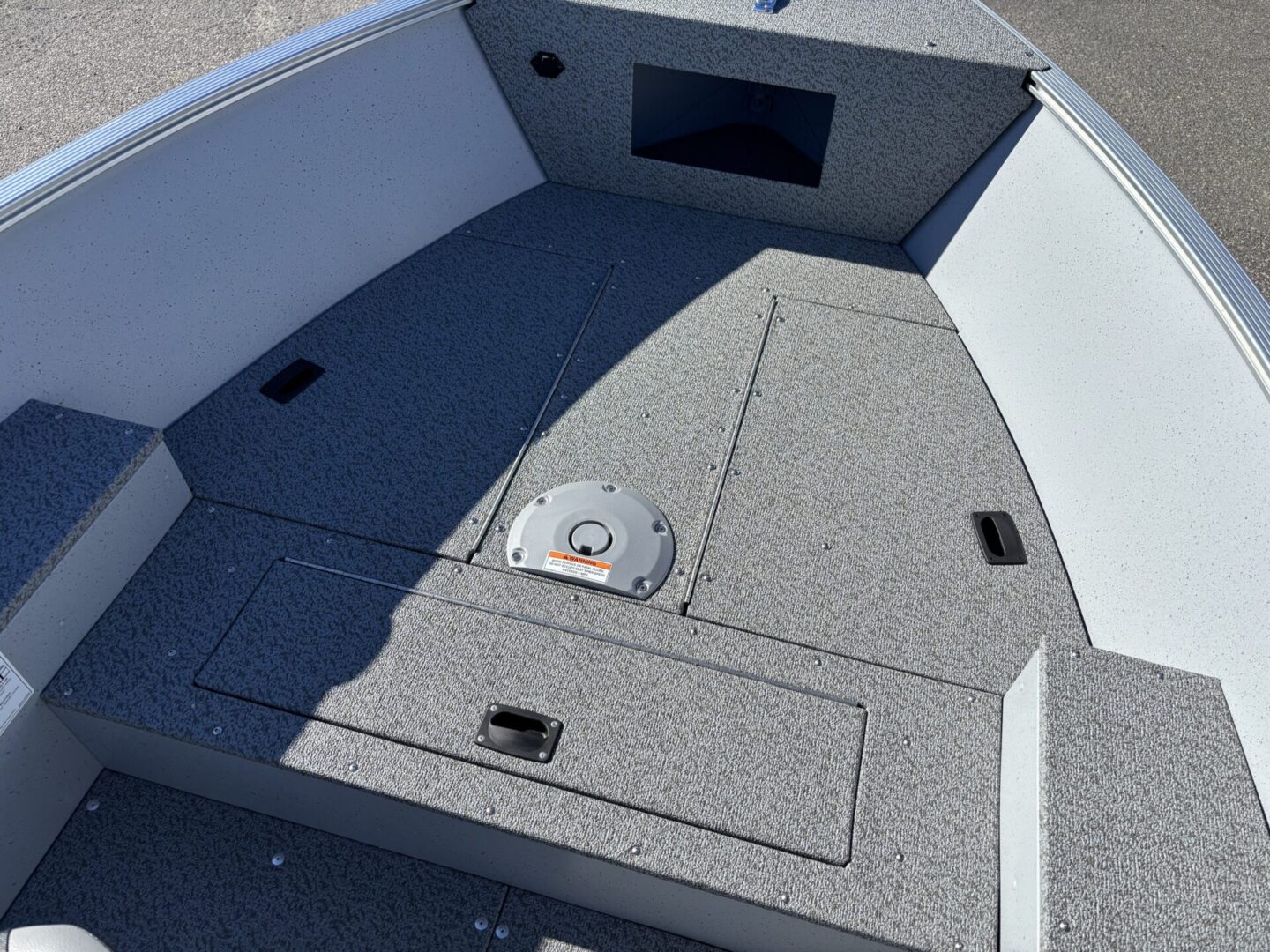 Front deck of a small fishing boat with storage compartments.