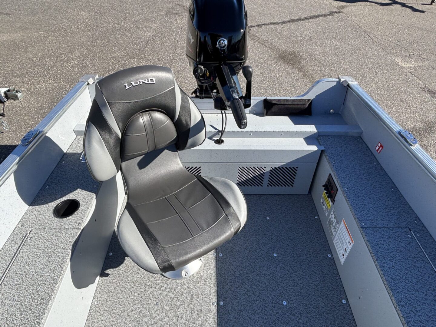 A gray boat seat with a motor in the background on a sunny day.